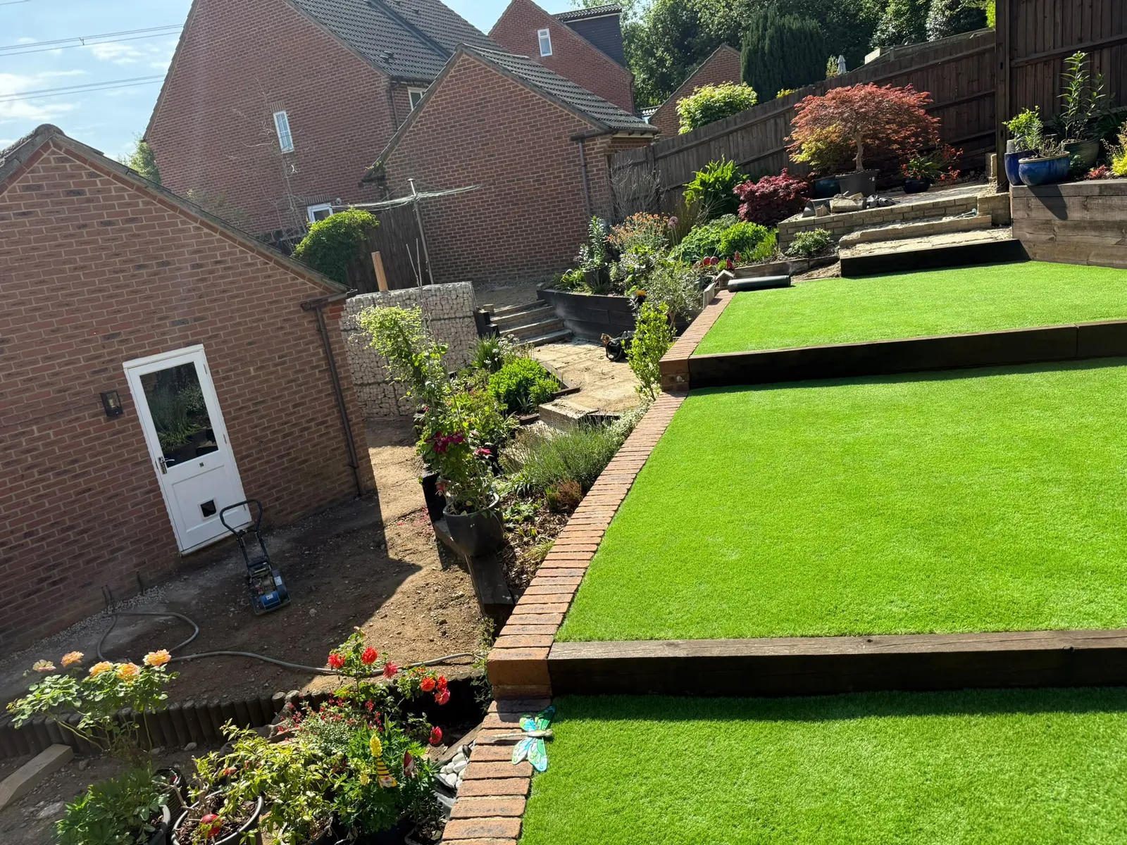 Tiered artificial lawn garden with brick edging and sleeper steps